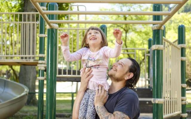 Student parent holding up child on playground