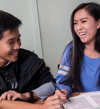 A tutor and student laughing and smiling while working