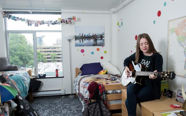 Female student playing guitar in her dorm room